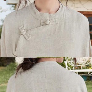 May include: A light beige linen shirt with a mandarin collar and a unique button closure. The shirt features a simple, elegant design with a relaxed fit. The fabric has a textured appearance, suggesting a natural fiber.