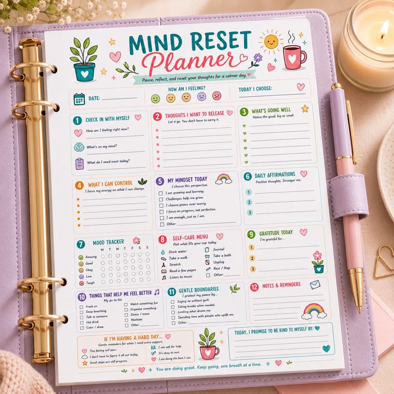 Puede incluir: Una p&aacute;gina de Mind Reset Planner dentro de una carpeta lavanda con un mecanismo de anillas dorado y un bol&iacute;grafo rosa. El papel blanco presenta encabezados coloridos, iconos y secciones para registros diarios, seguimiento de &aacute;nimo y gratitud.