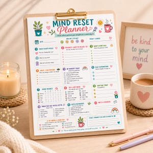 Puede incluir: Un portapapeles de madera con una hoja de Mind Reset Planner que incluye ilustraciones coloridas de plantas, un sol y una taza. El planificador presenta doce secciones numeradas para la reflexi&oacute;n diaria, el seguimiento del estado de &aacute;nimo y la gratitud.
