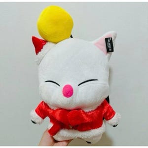 May include: A white plush cat toy in a red Santa suit with white trim and a yellow pom-pom. The cat has a pink nose, black eyes, and a red Santa hat. The tag reads "FINAL FANTASY XIV".