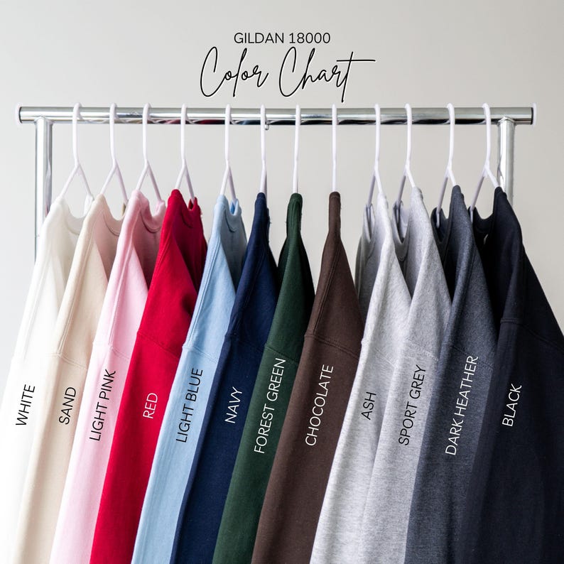 May include: A color chart of Gildan 18000 sweatshirts in various colors, including white, sand, light pink, red, light blue, navy, forest green, chocolate, ash, sport grey, dark heather, and black. The text "Color Chart" is displayed above the sweatshirts.