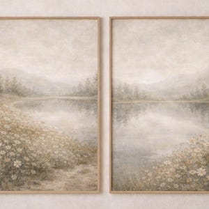 Può includere: Due stampe artistiche incorniciate di paesaggi. Ogni stampa raffigura una serena scena lacustre con montagne sullo sfondo. Il primo piano presenta un campo di fiori selvatici bianchi e gialli. L'opera d'arte è in tenui tonalità di beige, grigio e verde.