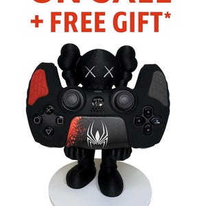 Pode incluir: Controlador preto com detalhes vermelhos e um gráfico de aranha, montado em uma base branca. O controlador tem um design exclusivo com uma cabeça de personagem e o texto "ON SALE + FREE GIFT*" em vermelho.
