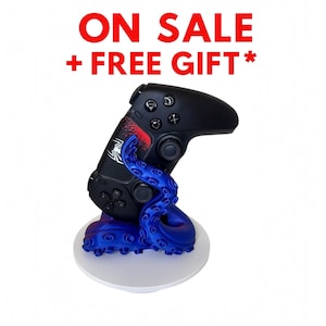 May include: Black gaming controller on a blue tentacle-shaped stand. The controller has a red and white design and the text "ON SALE + FREE GIFT*" in red.