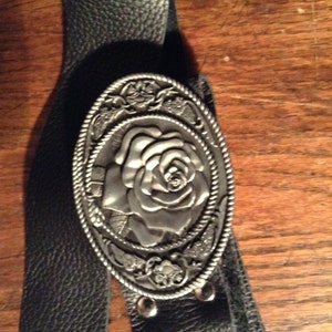 Black leather belt with a metal rose buckle.