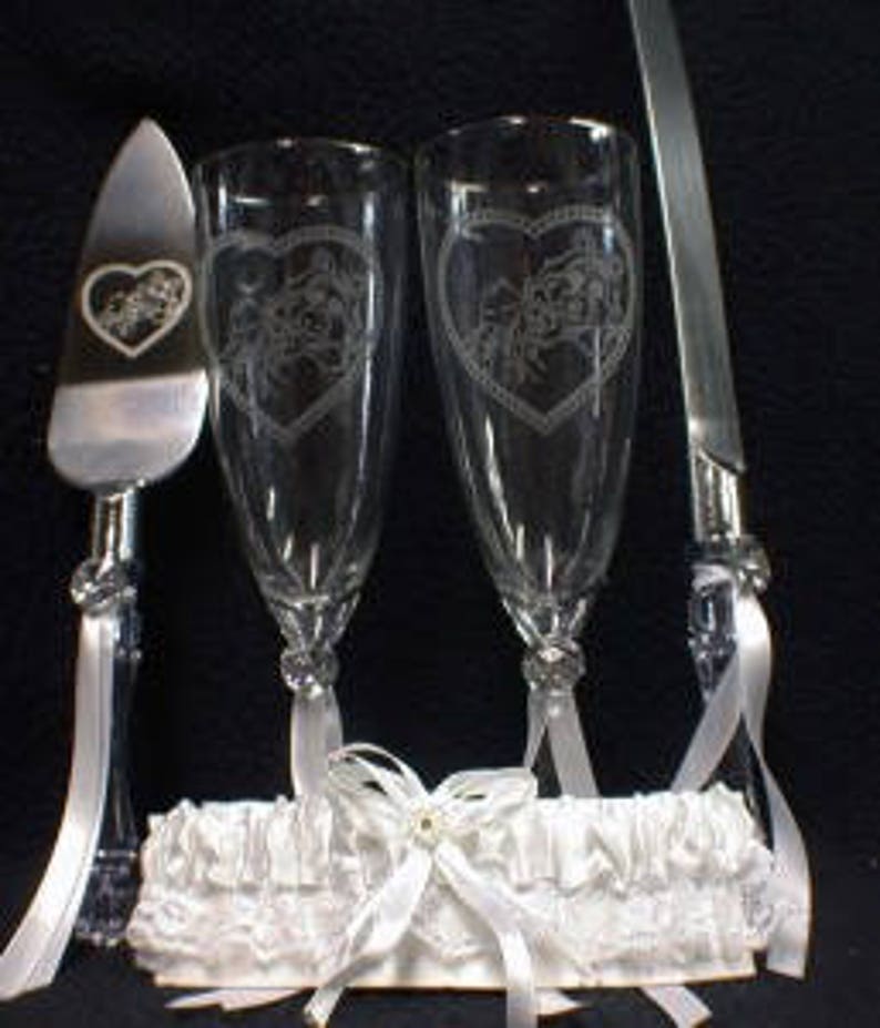 Puede incluir: Un juego de servir pastel de boda con dos copas de champ&aacute;n, un cuchillo para pastel y una liga blanca. Las copas y el cuchillo est&aacute;n grabados con un dise&ntilde;o de coraz&oacute;n.
