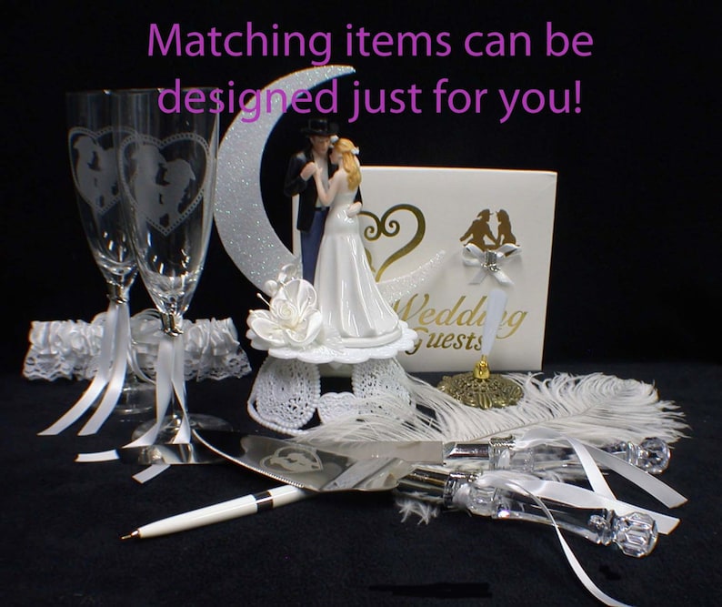 May include: Wedding cake topper set with a bride and groom figurine, a cake knife and server, two champagne flutes, a white feather boa, and a white lace garter. The cake topper features a crescent moon and the words "Wedding Guests".