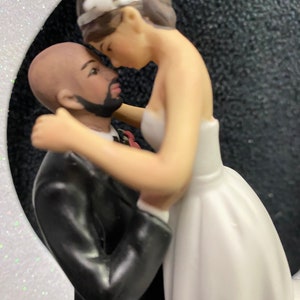 Pu&ograve; includere: Un topper per torta nuziale con una sposa e uno sposo che si abbracciano. La sposa indossa un abito bianco e lo sposo indossa un abito nero. La coppia &egrave; in una posa di abbraccio romantico.