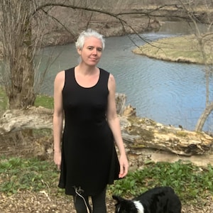 May include: A sleeveless black dress with a scoop neckline and a flared skirt that falls above the knee. The garment is made of a solid black fabric and features a simple, fitted bodice that transitions into a relaxed, flowing skirt silhouette.