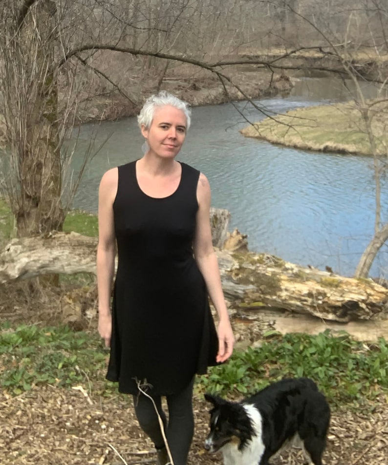 May include: A sleeveless black dress with a scoop neckline and a flared skirt that falls above the knee. The garment is made of a solid black fabric and features a simple, fitted bodice that transitions into a relaxed, flowing skirt silhouette.