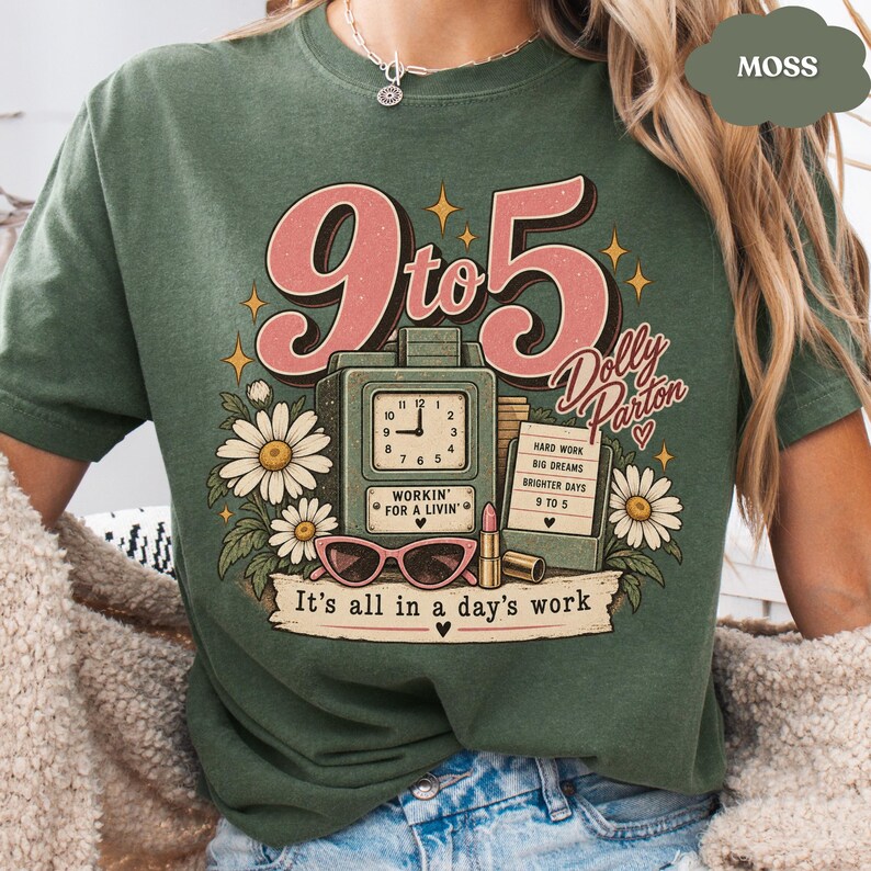 May include: A moss green t-shirt featuring a graphic with the text 9 to 5, Dolly Parton, Workin' for a livin', and It's all in a day's work. The design includes a clock, a sign, daisies, a lipstick tube, and pink cat-eye glasses.
