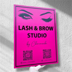 Puede incluir: Un letrero rosa brillante con texto negro que dice "LASH & BROW STUDIO" y "by Chervonenko". El letrero presenta ilustraciones de pestañas y cejas. Dos códigos QR y nombres de usuario de redes sociales en la parte inferior.