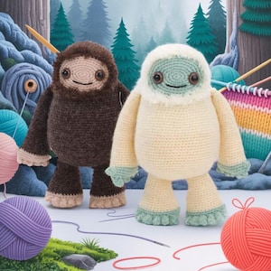 May include: Two handmade crochet Bigfoot dolls. One is brown, the other is cream-colored with a light blue face and accents. They have smiling faces and are standing in front of a forest backdrop. Yarn and knitting needles are in the background.