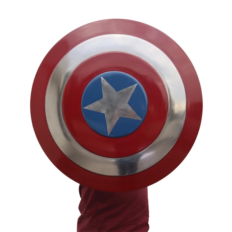 May include: A red, white, and blue shield with a silver star in the center. The shield has a circular design with concentric rings of red, silver, and red. The center features a blue circle with a silver star.