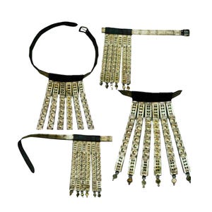 May include: Four pieces of ornate, silver-toned jewelry with black leather straps. Each piece features rectangular, decorative elements with a repeating pattern, hanging in vertical rows. Some pieces have small, dangling beads at the bottom.