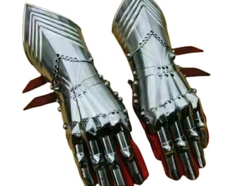 May include: Pair of polished steel gauntlets, featuring articulated fingers and a detailed, layered design. The gauntlets have a bright, reflective surface and are lined with red fabric. The overall design suggests medieval armor.