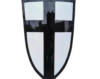 May include: A medieval shield with a black and white cross design. The shield has a black border with rivets and a curved, pointed bottom. The cross is centered, with white squares on a black background.