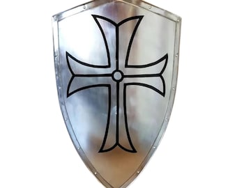 May include: A silver-colored shield with a black cross design. The shield has a pointed bottom and a rounded top, with rivets along the edges. The cross is centered and has flared ends.