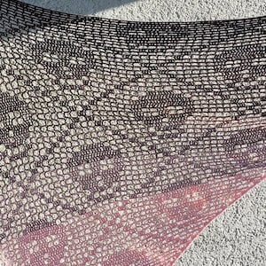 Könnte beinhalten: Ein handgefertigter, offen gewebter Schal in einem Farbverlauf. Die Oberseite ist dunkelbraun, geht in ein helleres Braun über und dann in einen rosa Farbton am unteren Ende. Der Schal ist aus einem weichen, strukturierten Material gefertigt.