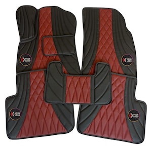 Puede incluir: Juego de cinco alfombrillas negras y burdeos para coche. Las alfombrillas tienen un patrón de diamante acolchado en burdeos con bordes y detalles en negro. Cada alfombrilla tiene un logotipo que dice "YOUR LOGO".