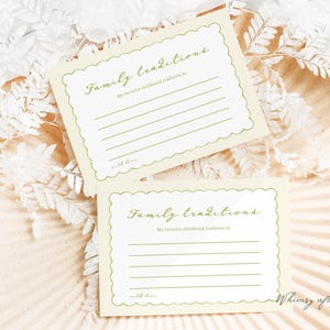 May include: Two cream-colored cards with scalloped edges, featuring the text "Family traditions" in green script. Each card has lines for writing and the phrase "My favorite childhood tradition is." The cards are on a textured surface.