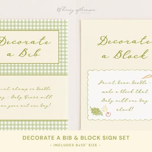 May include: Two cream-colored signs with green text and accents. One sign says "Decorate a Bib" and the other says "Decorate a Block". The signs are part of a set for baby activities.