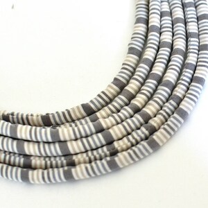 May include: A gray and white striped fabric necklace. The necklace is made of multiple strands of fabric that are woven together.