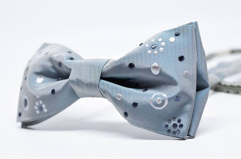 Peut inclure: Un n&oelig;ud papillon bleu clair avec un motif de pois blancs et argent&eacute;s.