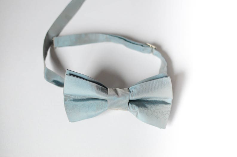 Peut inclure: Un n&oelig;ud papillon bleu clair en tissu. Le n&oelig;ud papillon est nou&eacute; et pr&ecirc;t &agrave; &ecirc;tre port&eacute;.