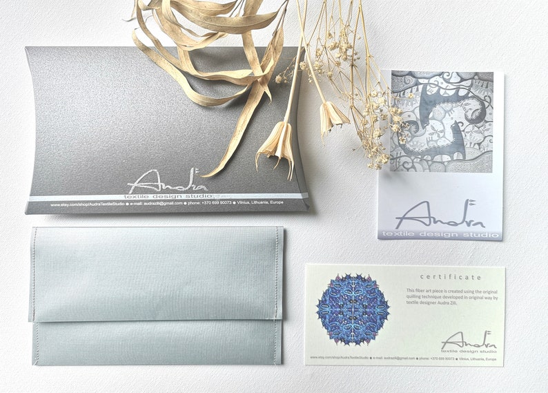 Peut inclure: Un certificat d'authenticit&eacute; pour une &oelig;uvre d'art textile. Le certificat est imprim&eacute; sur du papier cartonn&eacute; blanc avec un motif de mandala bleu et blanc dans le coin sup&eacute;rieur gauche. Le texte indique "Certificat" et "Cette &oelig;uvre d'art textile est cr&eacute;&eacute;e en utilisant la technique textile originale d&eacute;velopp&eacute;e de mani&egrave;re originale par la cr&eacute;atrice textile Anda Zb." Le certificat est sign&eacute; "Anda" et comprend le nom de l'entreprise "Anda textile design studio" et les coordonn&eacute;es.