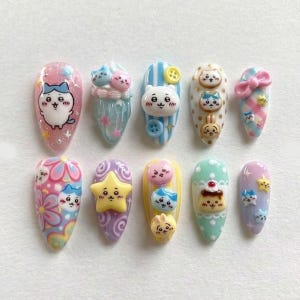 Könnte beinhalten: Eine Sammlung von zehn künstlichen Fingernägeln, die jeweils einzigartig mit Cartoon-Charakteren und dekorativen Elementen gestaltet sind. Die Nägel weisen verschiedene Farben auf, darunter Rosa, Blau, Gelb und Lila, mit Glitzer und 3D-Verzierungen wie Sternen, Schleifen und Knöpfen.