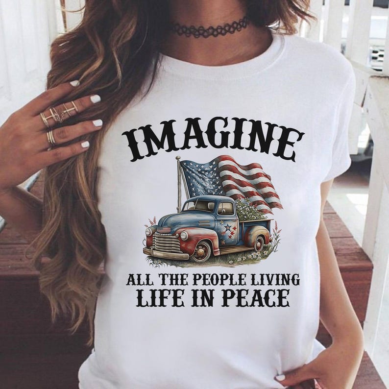 K&ouml;nnte beinhalten: Wei&szlig;es T-Shirt mit patriotischem Design. Die Grafik zeigt einen blauen und roten Oldtimer-Truck mit Blumen und einer amerikanischen Flagge. Der Text lautet "IMAGINE ALL THE PEOPLE LIVING LIFE IN PEACE."