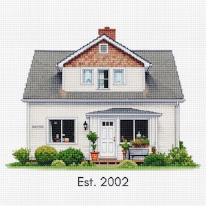 May include: A cross-stitch depiction of a two-story house with a gray roof, white siding, and a brick chimney. The house has a front porch with a bench and potted plants. The text "Est. 2002" is below the house.