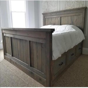 May include: A rustic, gray-stained wooden bed frame with a headboard and footboard. The bed features built-in drawers for storage and is covered with a white comforter. The design is a farmhouse style.