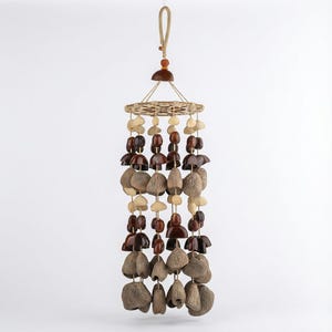 May include: A hanging mobile featuring a circular woven top with a natural fiber loop. The mobile is adorned with various shapes and sizes of wooden beads and natural seed pods in shades of brown and beige, creating a decorative piece.