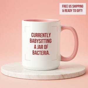 May include: A set of three ceramic mugs with a speckled, matte finish. The mugs are in shades of cream, light gray, and dark gray. Each mug has a simple, minimalist design and a rounded handle.