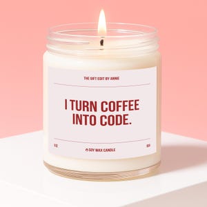 Könnte beinhalten: Eine brennende Sojawachskerze in einem durchsichtigen Glas. Auf dem Etikett steht "I TURN COFFEE INTO CODE." und "THE GIFT EDIT BY ANNIE." Die Kerze ist 9 oz und hat eine Brenndauer von 60 Stunden.