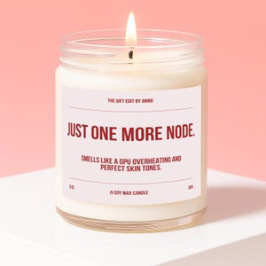 May include: A lit soy wax candle in a clear glass jar. The label reads "JUST ONE MORE NODE." and "SMELLS LIKE A GPU OVERHEATING AND PERFECT SKIN TONES." The candle is 9 oz and has a burn time of 60 hours.