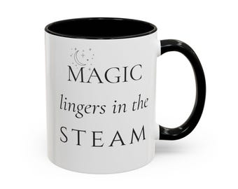 Puede incluir: Una taza de cerámica blanca con interior y asa de color negro. El exterior presenta un gráfico negro de una luna creciente y estrellas sobre el texto negro que dice: MAGIC lingers in the STEAM. La taza tiene una forma cilíndrica.