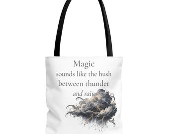 Puede incluir: Un bolso tote blanco con asas negras que presenta el texto "Magic sounds like the hush between thunder and rain" impreso en gris sobre una ilustración detallada de una nube oscura y tormentosa con rayos y lluvia cayendo.