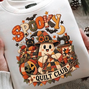 May include: A white sweatshirt featuring a graphic print with the text SPOOKY QUILT CLUB. The design includes a ghost wearing a witch hat, a black cat, a jack-o'-lantern, a sewing machine, and various quilt-themed elements in orange and brown.