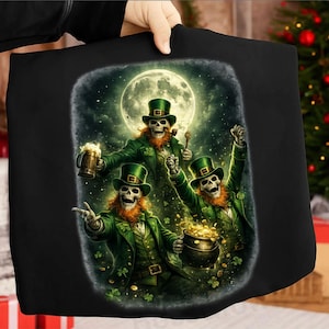May include: Black tote bag with a digital illustration of three skeleton leprechauns celebrating St. Patrick's Day. They wear green suits, hats, and have red beards, with a full moon in the background. One holds a mug of beer, another a pipe, and the third a pot of gold.