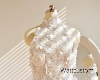 May include: A cream-colored, high-neck dress with intricate floral embellishments. The dress is displayed on a mannequin, with a mirror reflecting the dress. The text "Wattcustom" is visible on the dress.