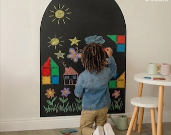 May include: An arched black wall decal featuring the Arka Doodle logo at the top right. The surface is covered in colorful chalk drawings of a sun, stars, a butterfly, a house, and flowers, alongside magnetic geometric shapes attached to the surface.