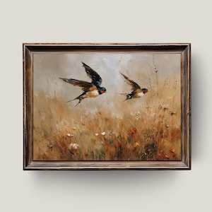 Könnte beinhalten: Ein gerahmtes Ölgemälde zeigt zwei Schwalben im Flug über einem Feld mit hohem Gras und Wildblumen. Die Vögel haben dunkle Flügel und rotbraune Markierungen. Das Kunstwerk verwendet eine warme, erdige Farbpalette.