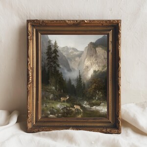 May include: An antique framed landscape painting depicting a mountain valley scene with deer near a stream. The painting features a gold ornate frame. The artwork showcases a serene natural environment with trees, mountains, and a river.