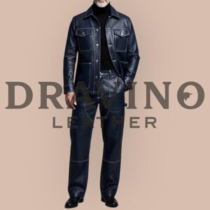 May include: A navy blue leather jacket and matching pants set with white stitching. The jacket has two chest pockets and two side pockets. The pants are straight-legged. The text "DRAMINO LEATHER" is visible in the image.