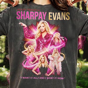 May include: Dark gray t-shirt featuring a graphic of Ashley Tisdale as Sharpay Evans. The design includes multiple images of her in pink outfits, with the text "SHARPAY EVANS" and "I WANT IT ALL! AND I WANT IT NOW!"