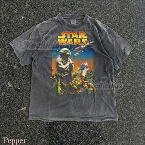 May include: A gray Star Wars t-shirt featuring Yoda, R2-D2, and a spaceship. The graphic is in vibrant colors against a faded gray background. The words "STAR WARS" are printed in yellow and orange.
