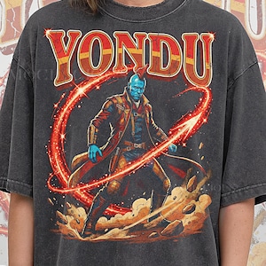 May include: Dark gray t-shirt featuring the word "YONDU" in a distressed, red and orange font. The graphic depicts a blue-skinned character with a red mohawk and a red energy arc. The text "PEPPER COMFORT COLORS" is at the bottom.